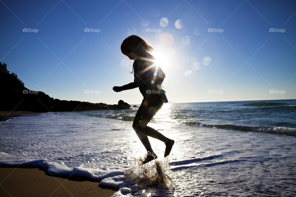 silhouette of a girl jumping from the sea shore