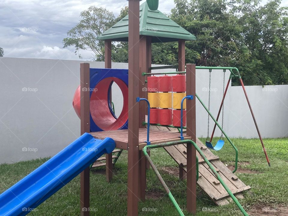 Parque infantil colorido. Parte construída com madeira, metal e uma parte feita com plástico resistente.