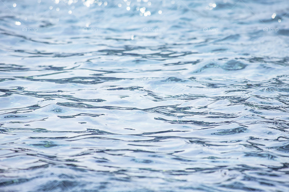 The blue water waves by wind and sunlight reflecting surface