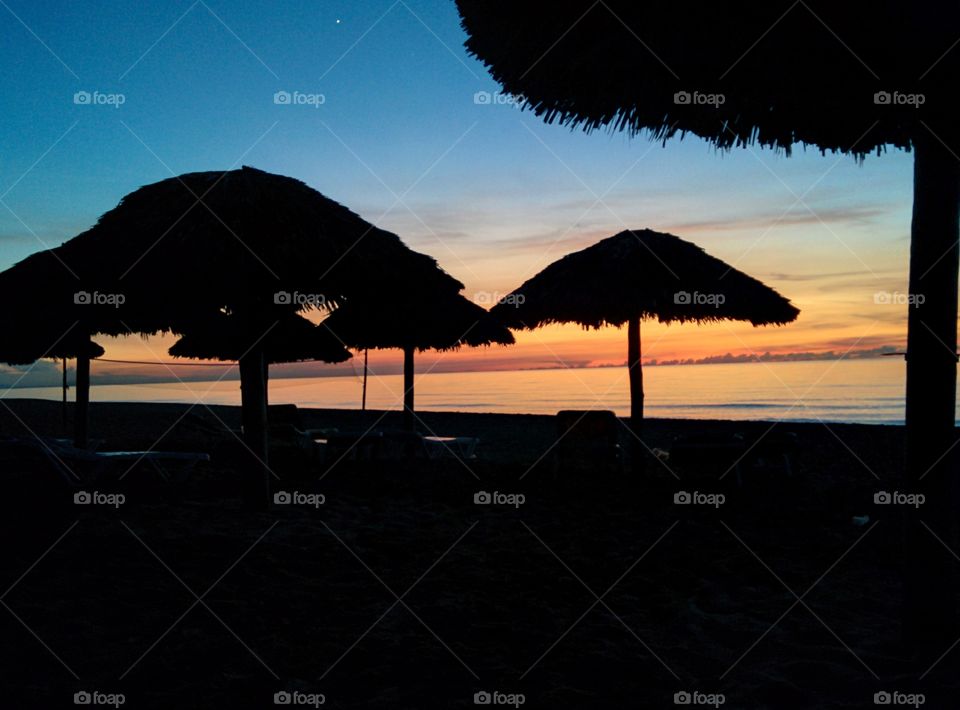 Shades of beach umbrellas at a beautiful sunset by the ocean