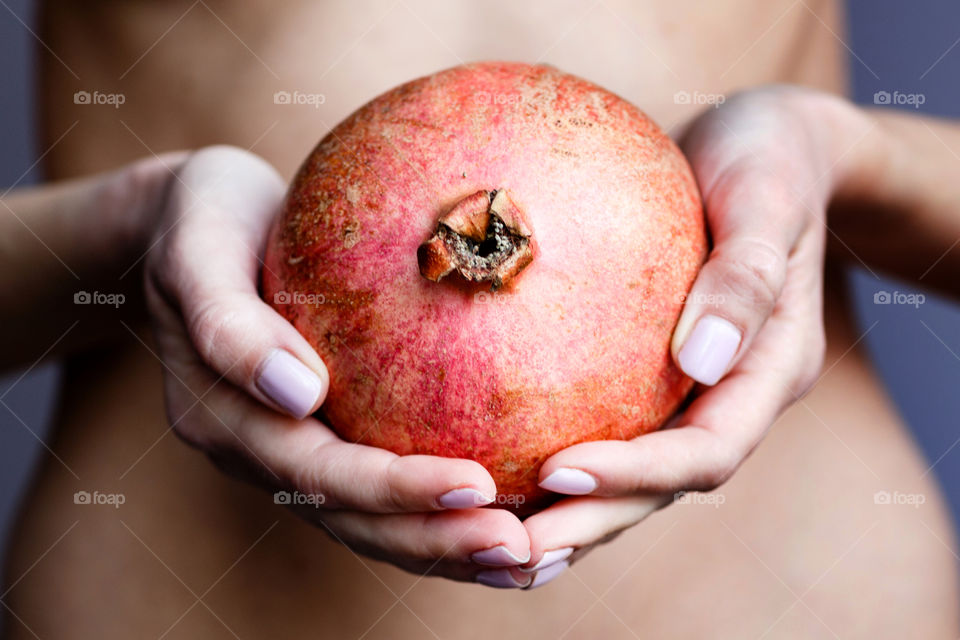 Woman’s hands holding fresh pomegranate 