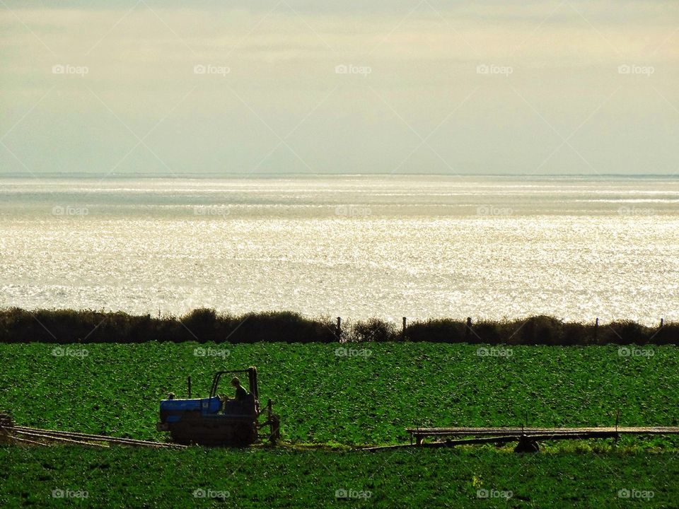 Tractor tilling a farm near the ocean