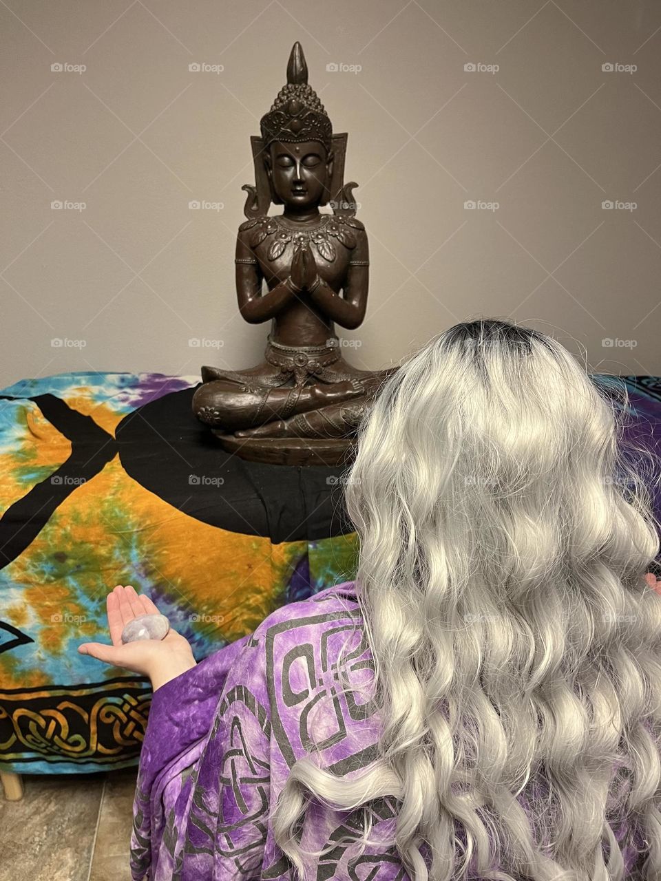 A woman meditating in front of a Buddha statue.