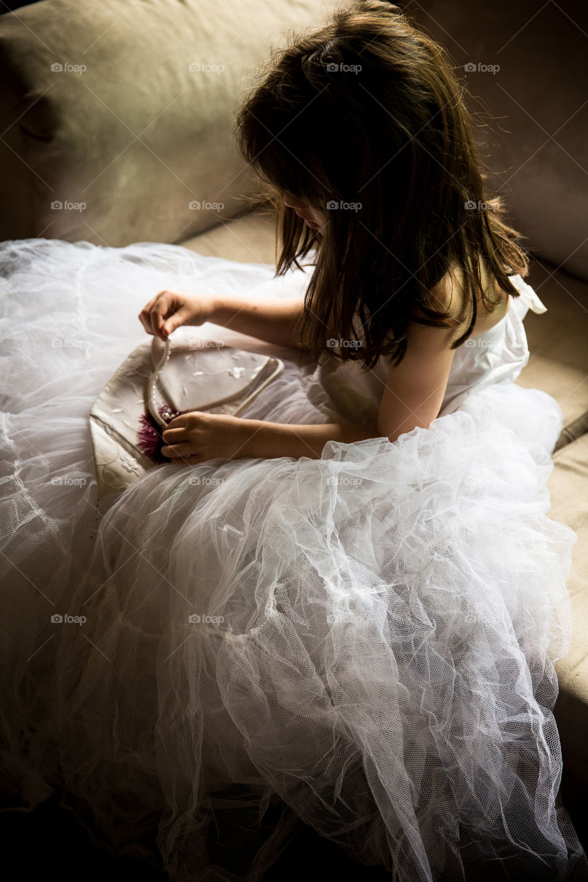 Fun at home - my girl playing dress up in wedding dress and accessories. Image of girl sitting in wedding dress playing with pearls from a handbag.