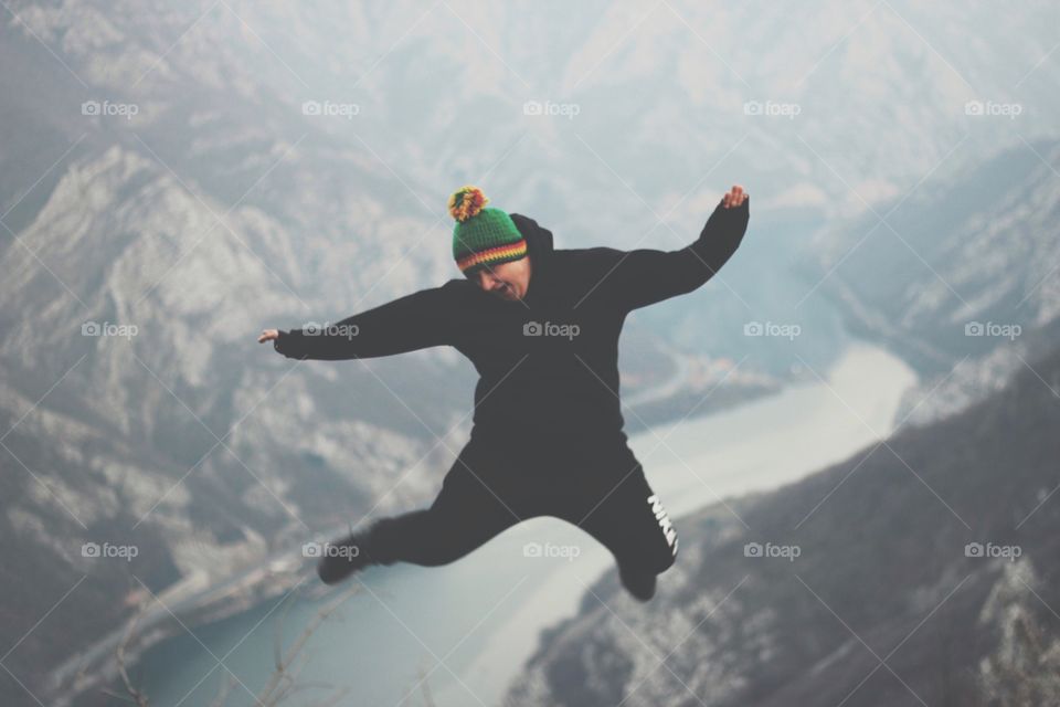 Happy man jumping near mountain