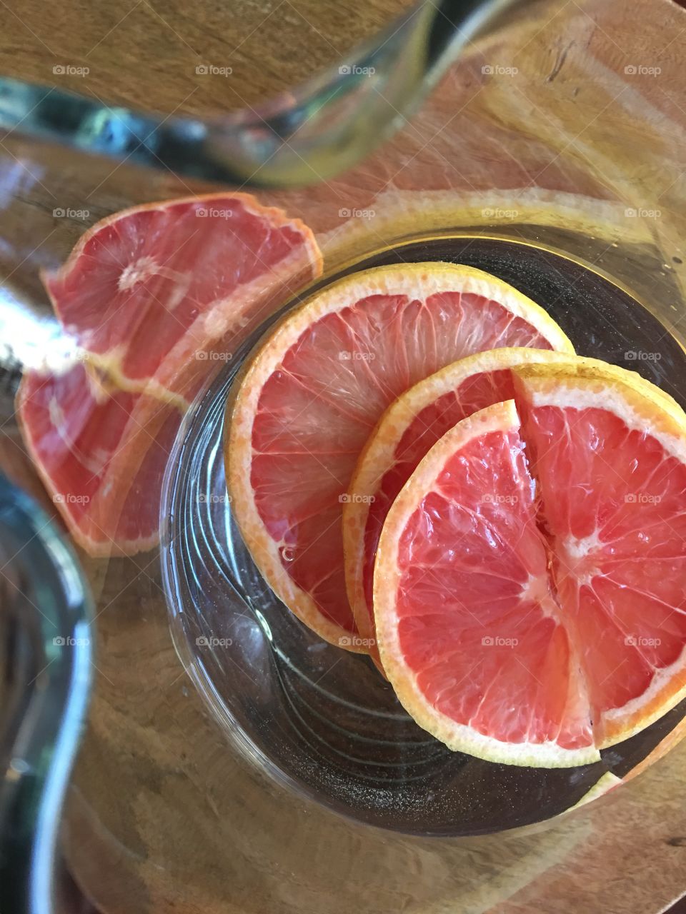 Close up pitcher of water with fresh grapefruit slices.