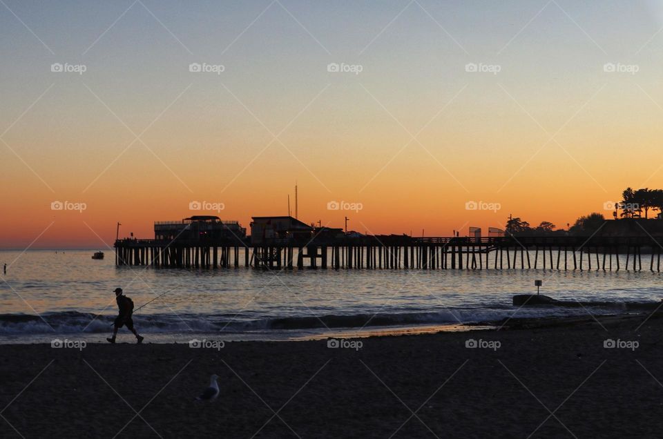 Sunset at Capitola Beach in California, with the soft glow giving a silhouette of the wharf jutting out into the ocean 