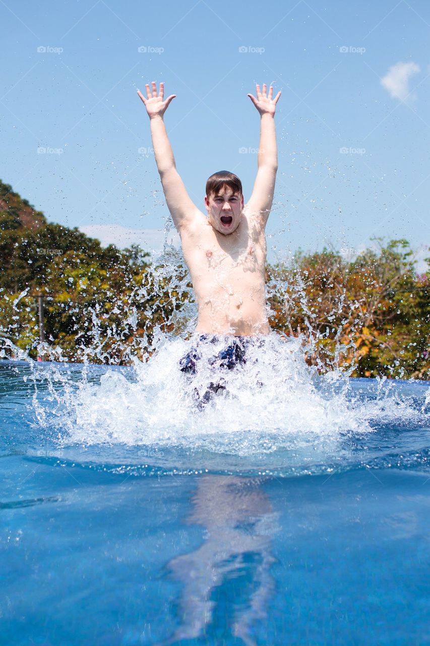 Man jumping through water in the swimming pool