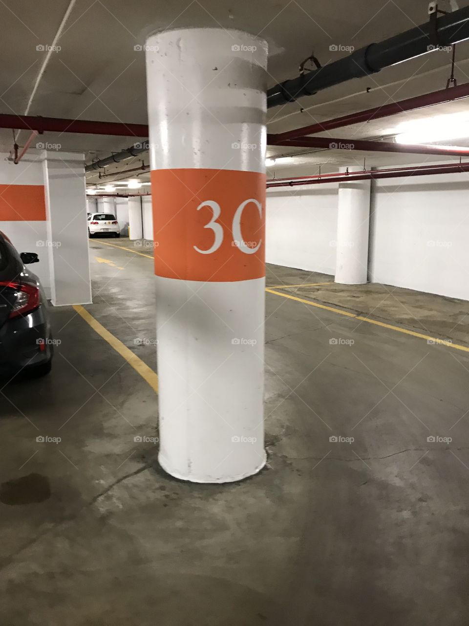 An empty underground parking lot with pillars and a big 3c sign on a support pole