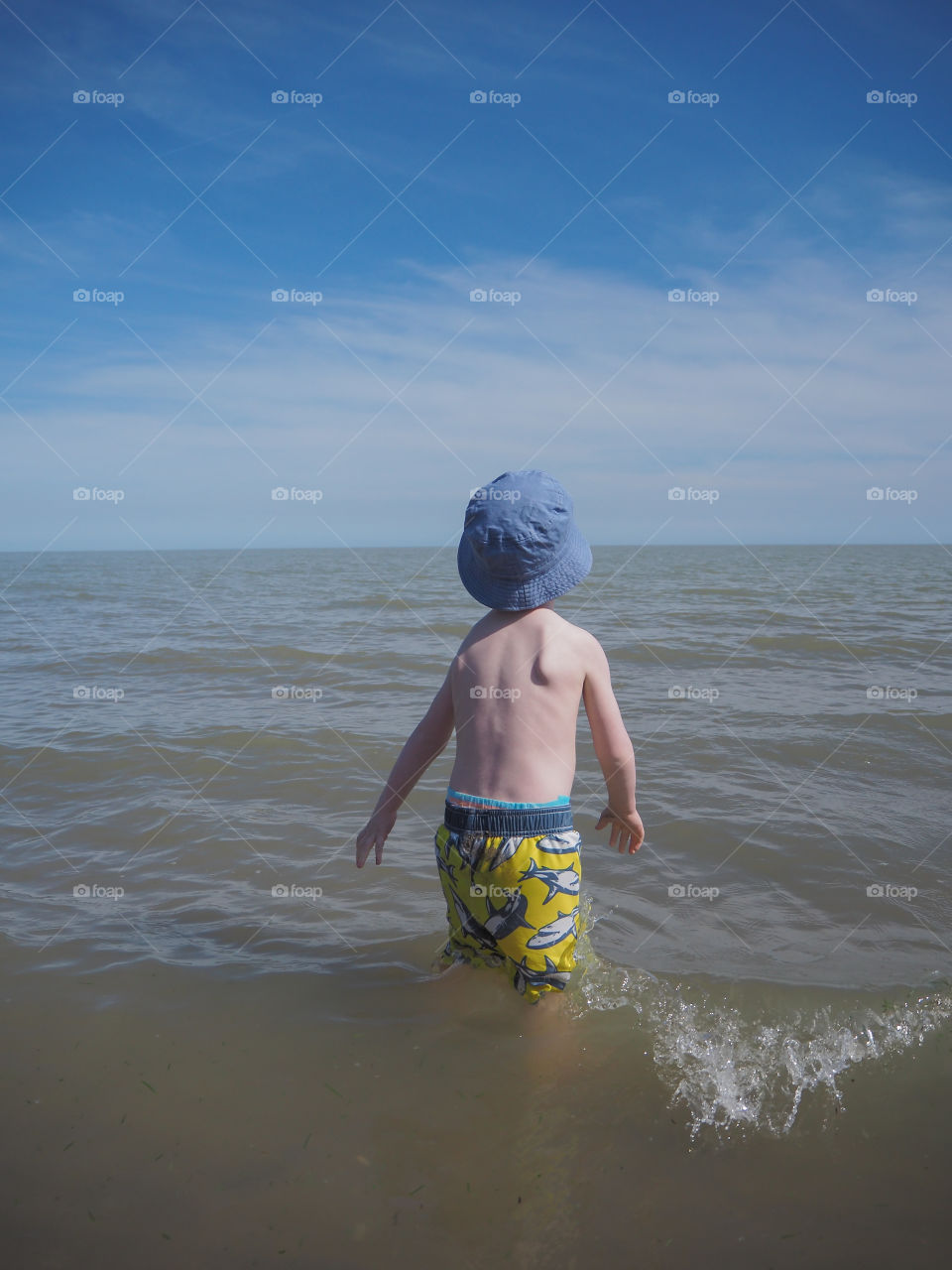 Toddler boy playing in the gentle waves at the beach shores of Port Burwell, Ontario, Canada