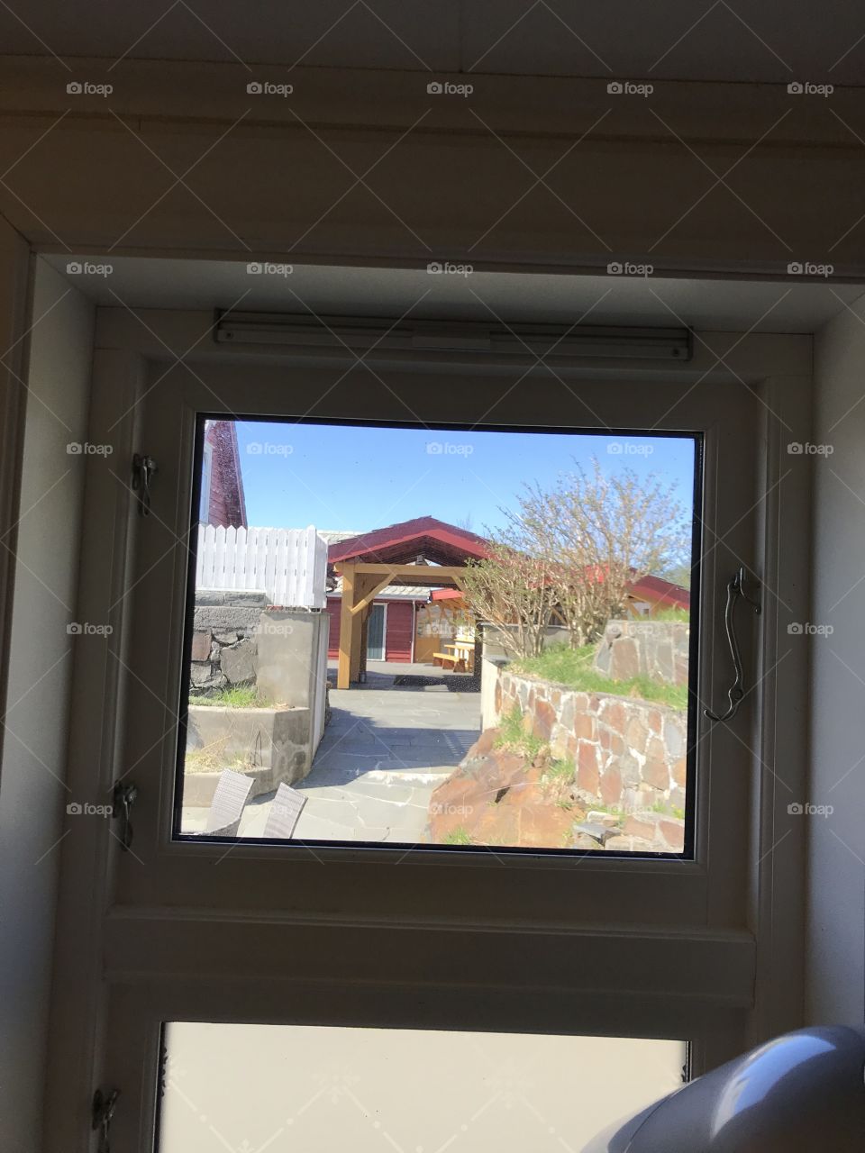 Peeking out the window to a cozy red roof, some wooden benks, and clear, super blue skies.