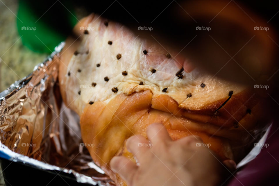 Woman placing cloves into ham, preparing Christmas dinner, making dinner on a special occasion, traditional ham meal, family dinner on Christmas, preparing delicious food, cloves in ham, flavoring with clove 