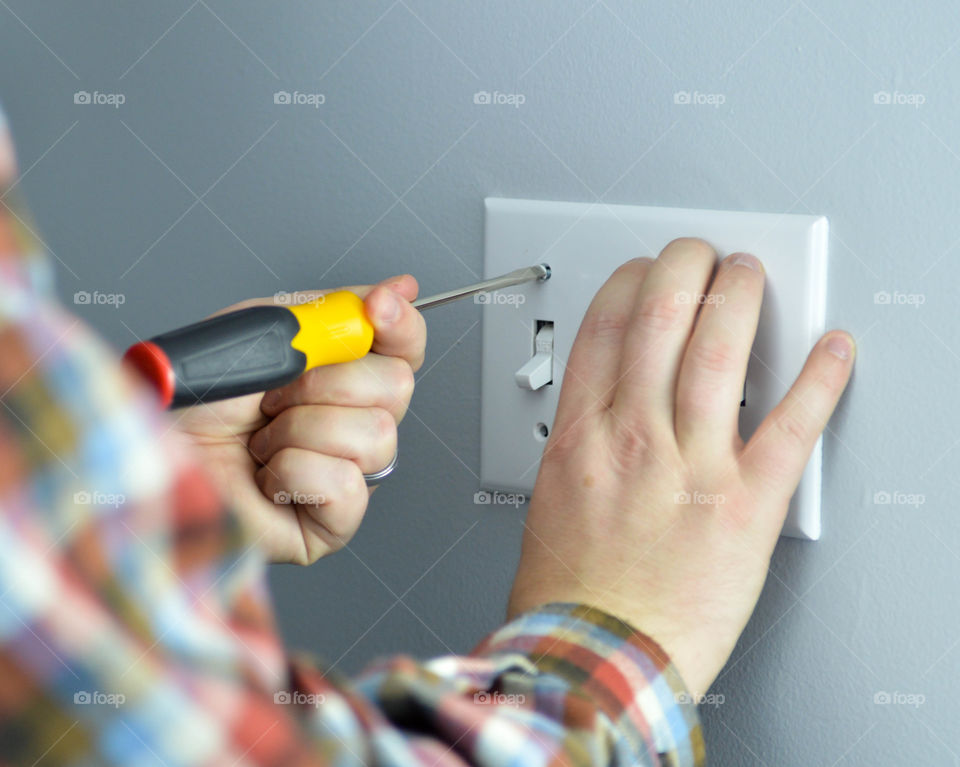 Handyman screwing on a light switch plate