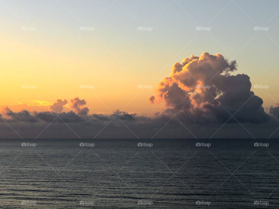 Early morning sunlight on clouds at ocean horizon 