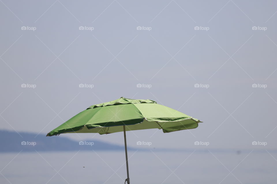 Green beach umbrella against the sky