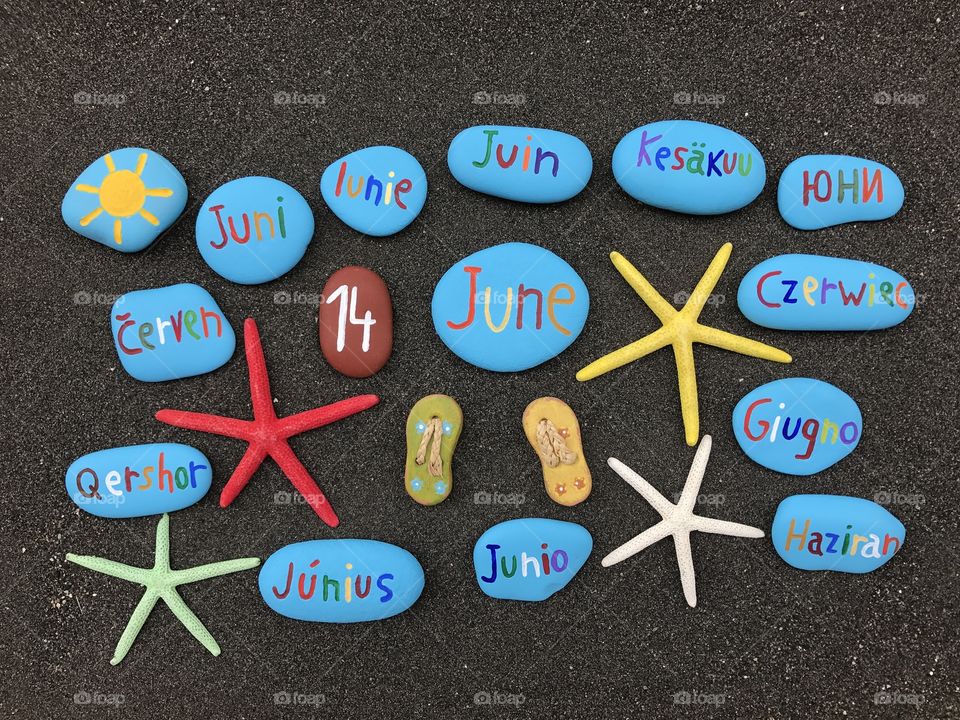 14 June, calendar date with multicolored stones and starfishes over black volcanic sand