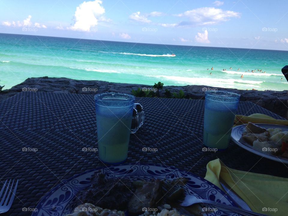 picture perfect beach with amazing blue water and a tasty beverage in cancun mexico. 