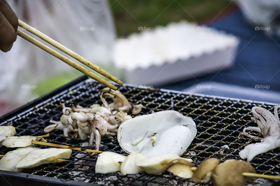 Fresh squid and mushrooms on the grill grate steel.