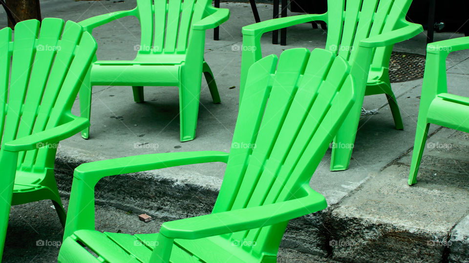 Green plastic lawn chairs on cement stairs outdoors in urban setting conceptual gathering and relaxation summertime city life background photography