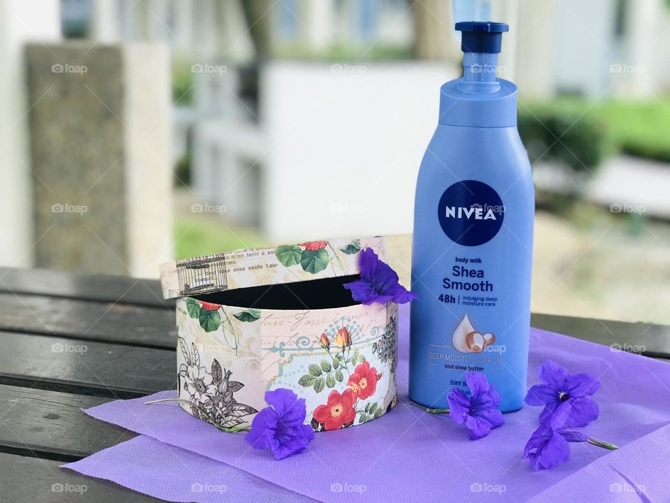 Nivea cream with gift box and purple colour sheet and flowers.