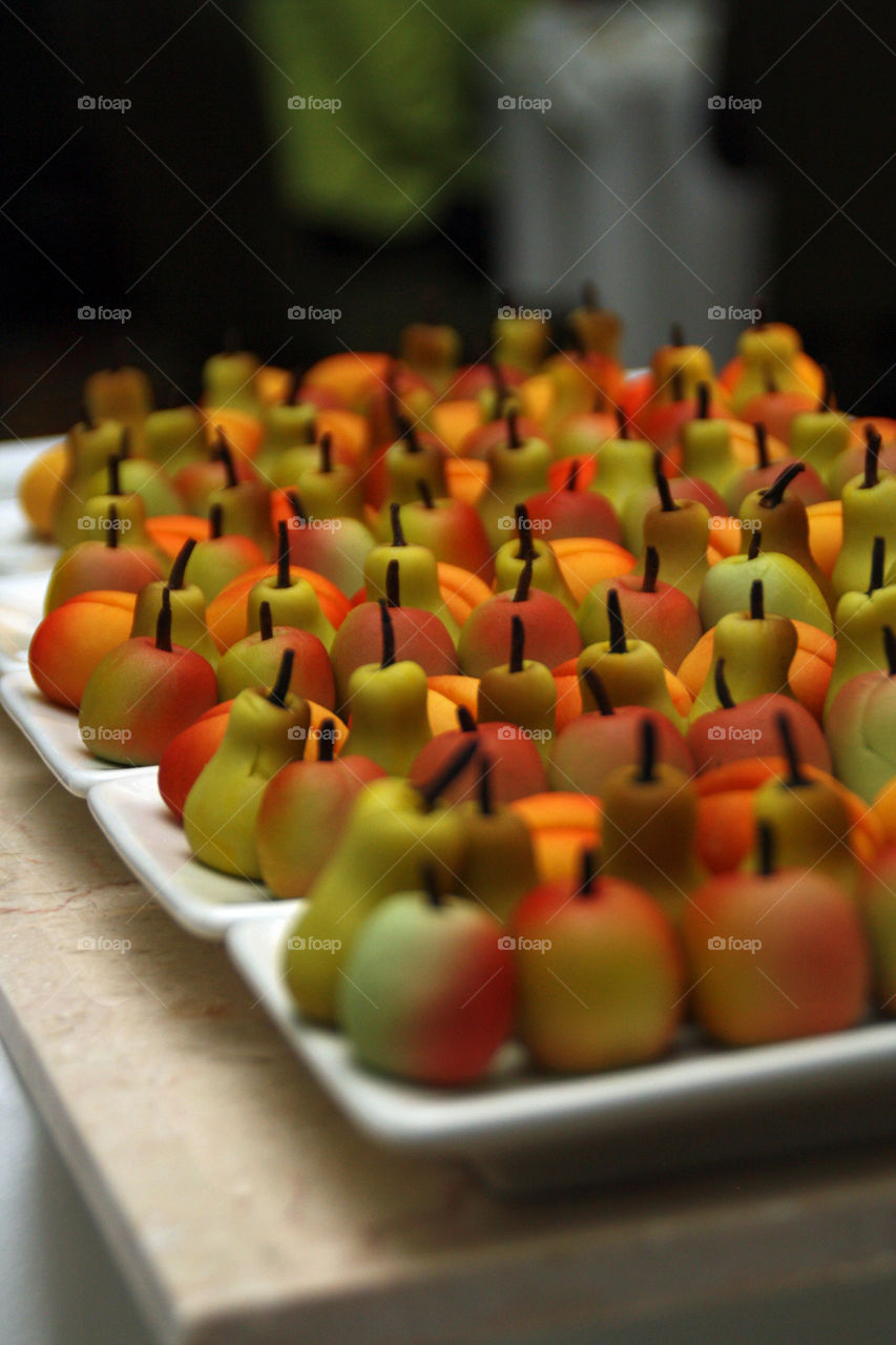 Many small marzipan desserts shaped like fresh fruit