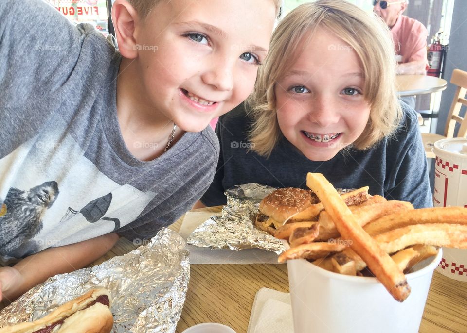 Close-up of brother and sister eating french fries and burger in restaurant