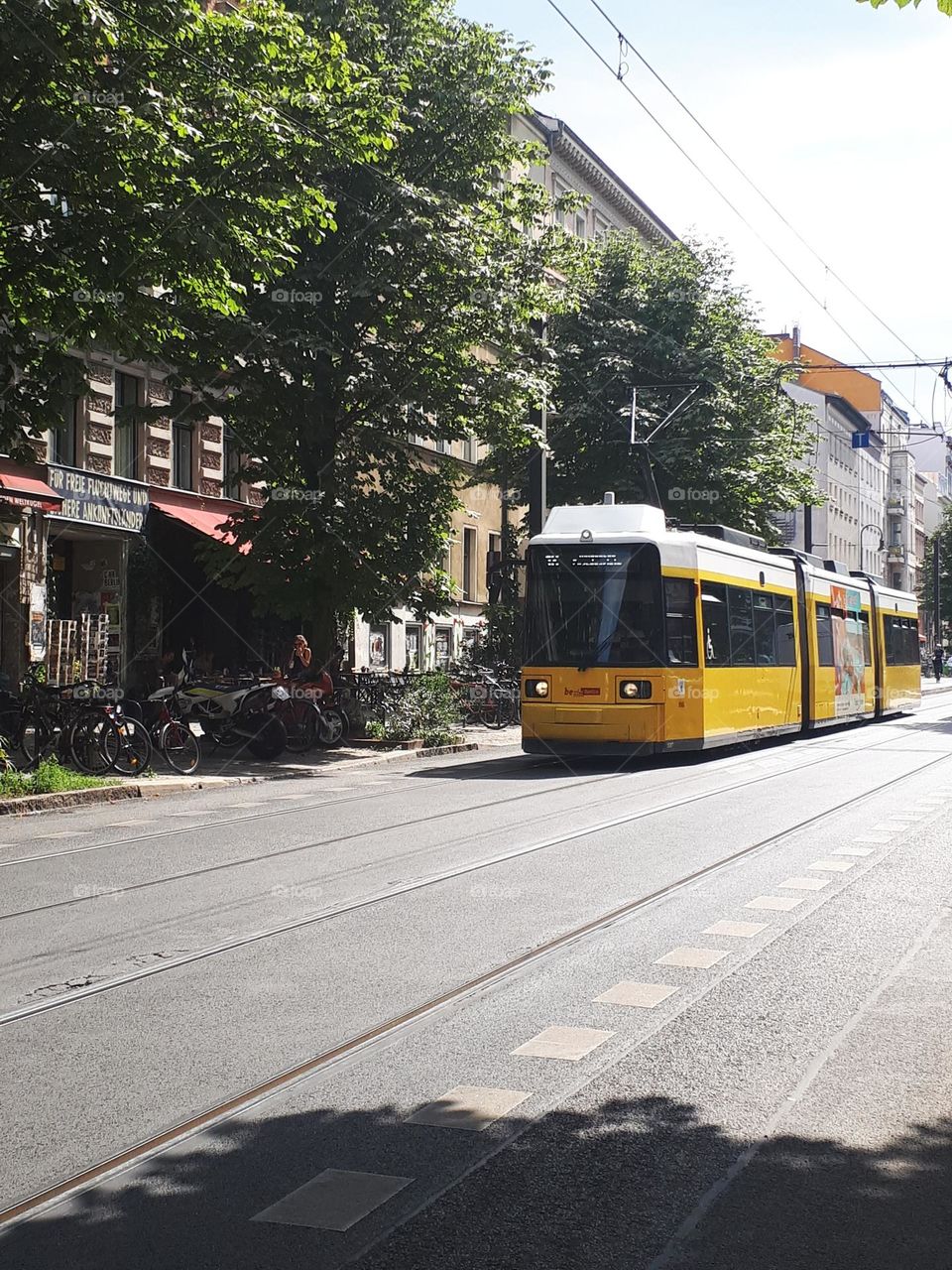 Yellow tramway passing through city street with bikes parked on the side.