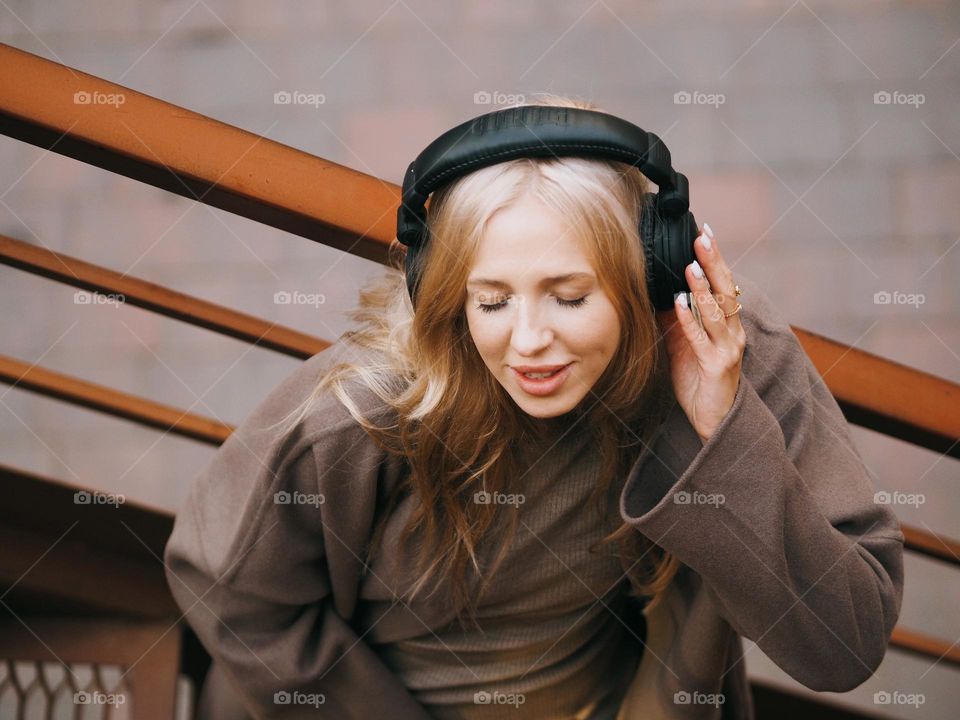 Young beautiful blonde woman in headphones, listen music with closed eyes, portrait of woman 