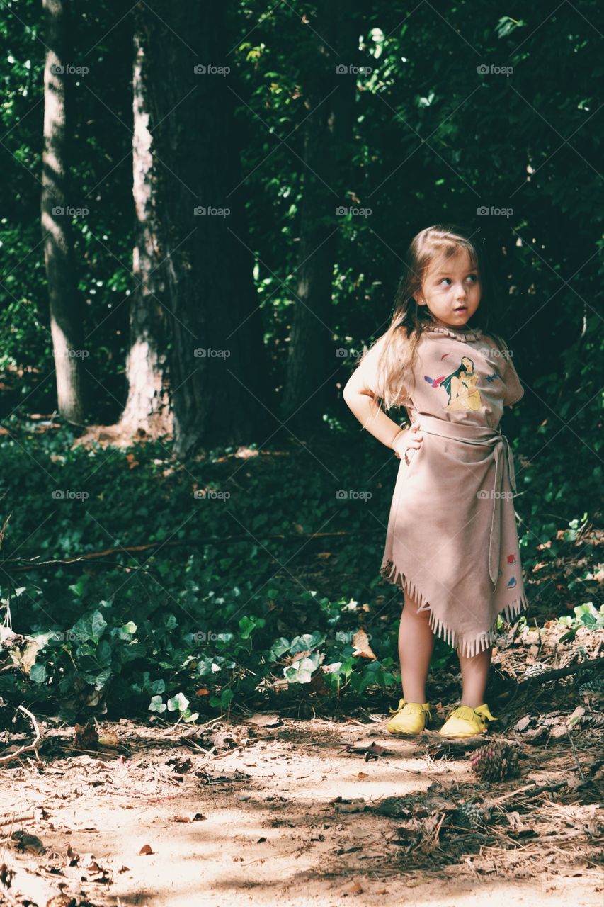 Cute little girl standing near trees