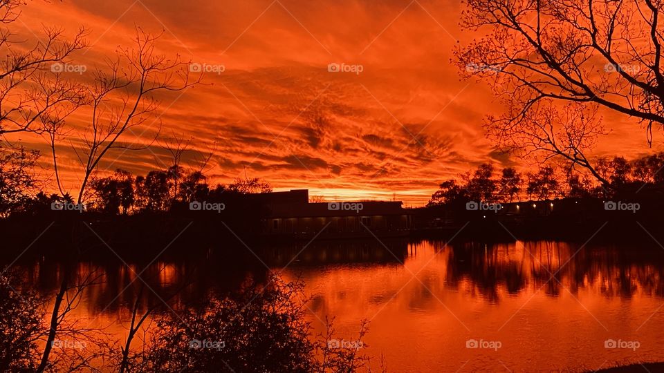 Fiery Red Ending of a Beautiful Twilight after a gorgeous Sunset. Now Night is Now Reflections, Silhouettes, Captivating Fiery Sky over Lake Waters.