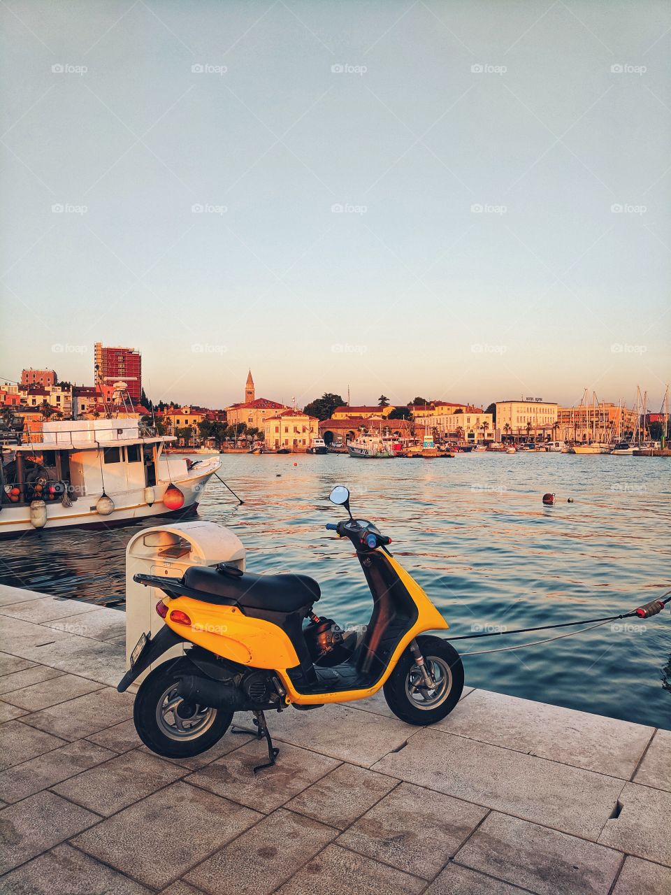Yellow scooter stands on the embankment by the sea