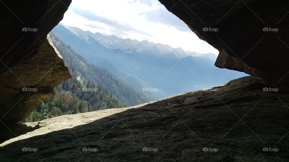 view of mountain range through crack in rocks