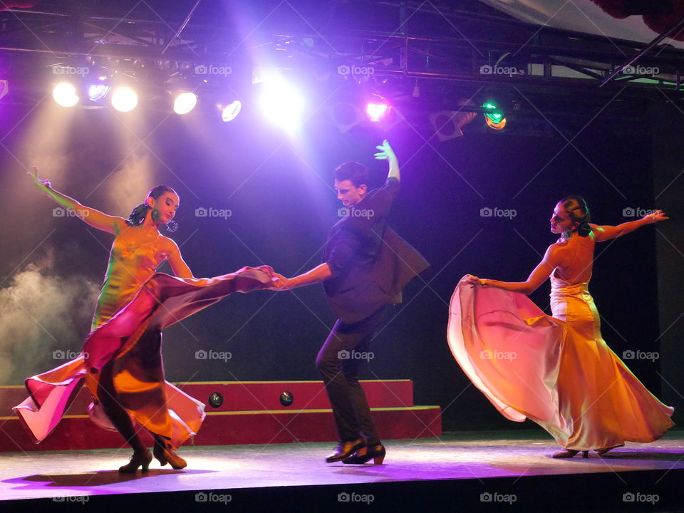 Man dancing with two women on the stage