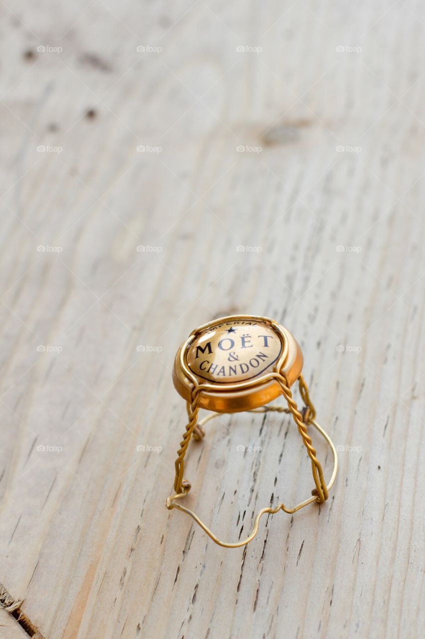 The top of a champagne bottle sits alone on a wood surface after having been removed and the bubbly was poured