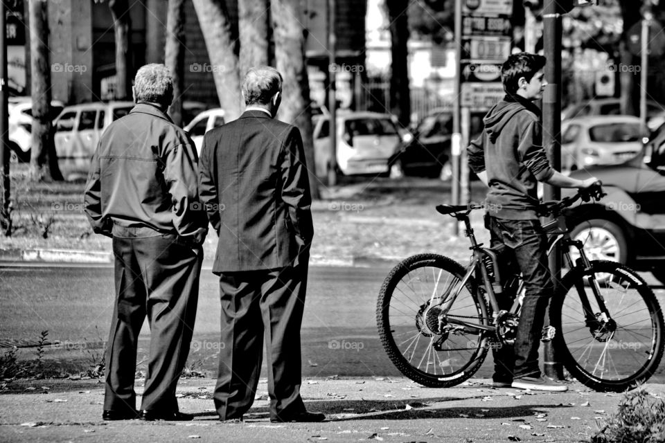 a pair of old men talk standing on the sidewalk