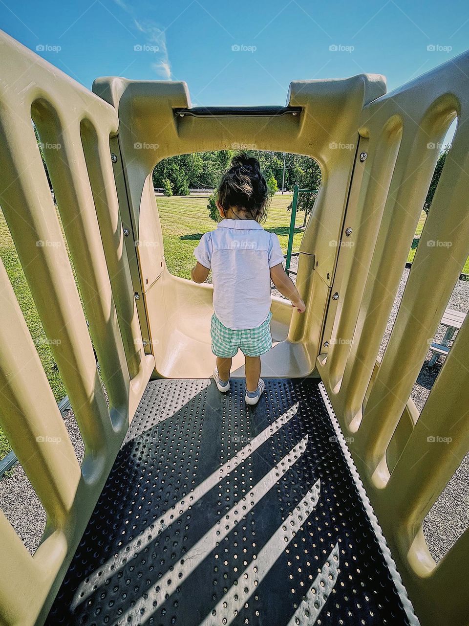 Toddler girl goes down a big slide, slides on playgrounds in parks, having fun in the park 