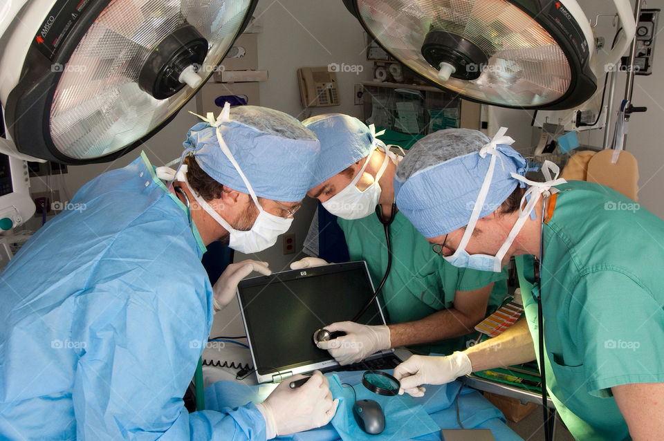 Three men operate on a computer in an emergency room at the hospital