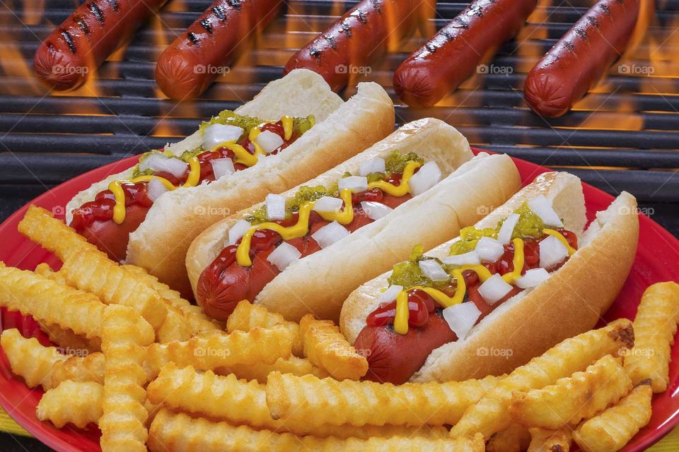 Hotdogs next to a flaming hot grill