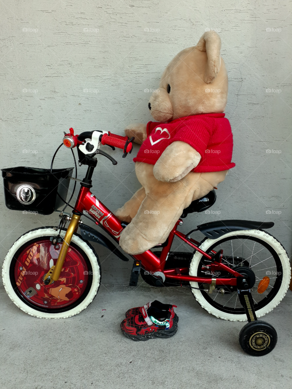 bear on the red iron man bike with spider man shoes.