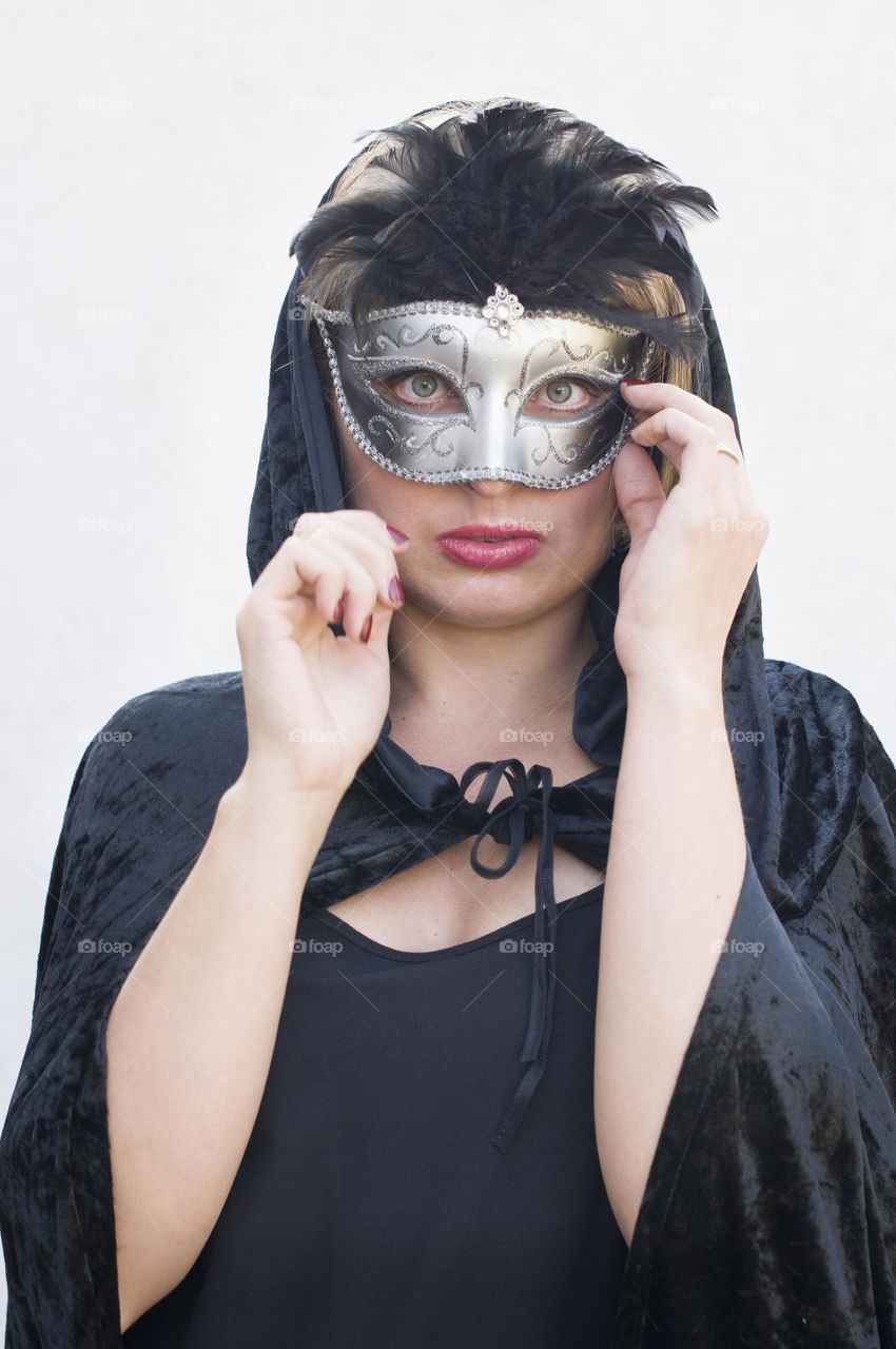 beautiful mysterious girl in black cloak and carnival mask, mardi gras parade