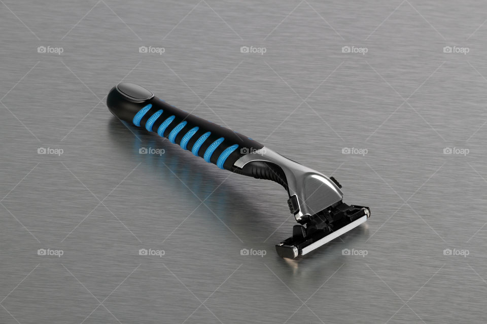 Razor with blade on brushed steel background