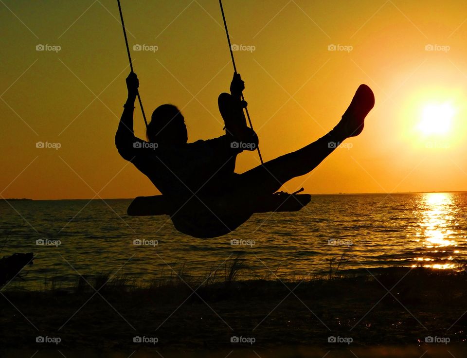 World of silhouettes and shadows  - A beautiful woman silhouetted against the sunset on an idyllic beach swinging in the summer breeze. What a wonderful way to convey drama, mystery, emotion and mood in a picture by posting a silhouette 