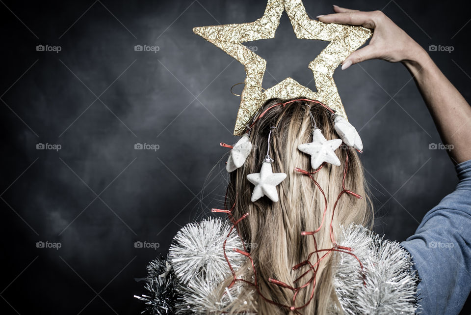 Portrait of a woman standing with her back to the viewer. Decorated like a Christmas tree