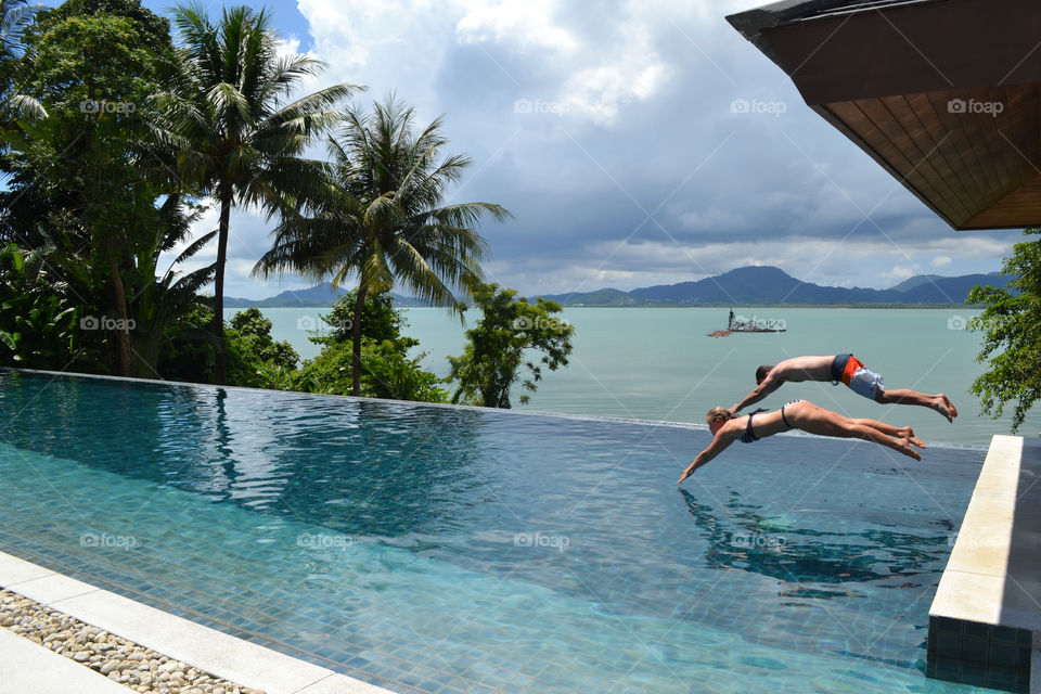 Diving into the infinity pool with an ocean background 