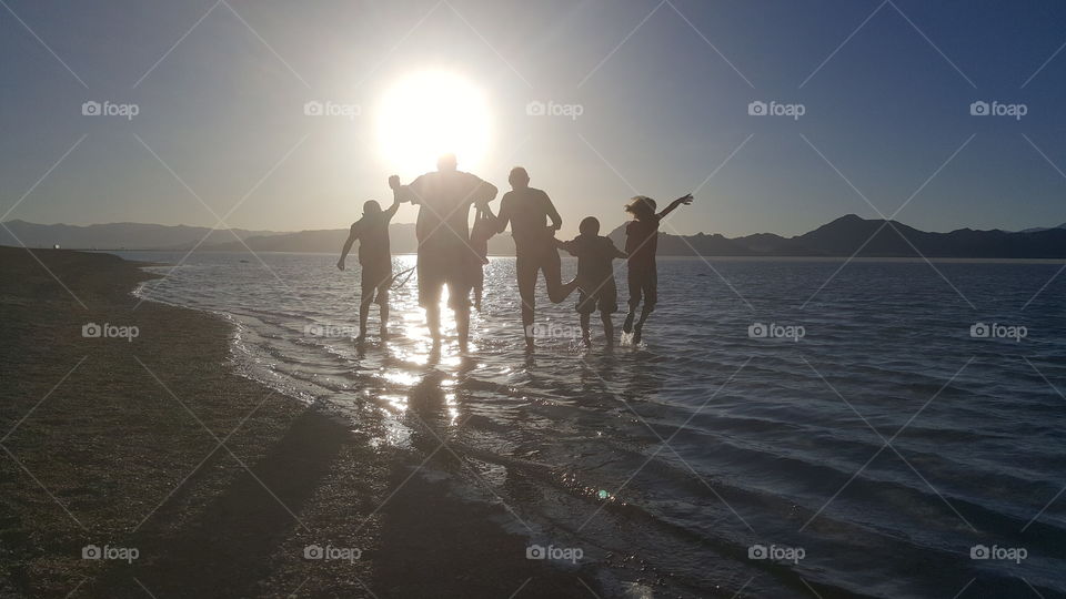 family leaping silhouetted on the beach with mountains in the background fun playing the Great Salt Lake near Salt Lake City Utah United States of America 2017