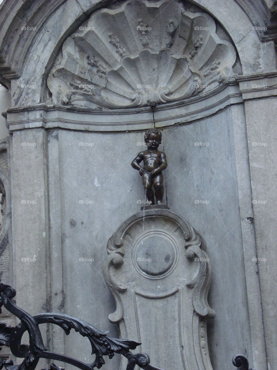 Manneken Pis. Literally - Little Man Pee. Bronze fountain sculpture of a maked little boy urinating into the fountain's Basin