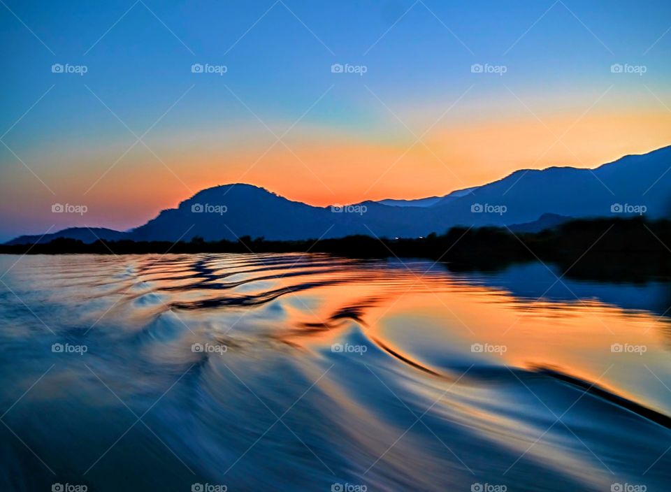 Silhouette of mountain range during sunset near sea