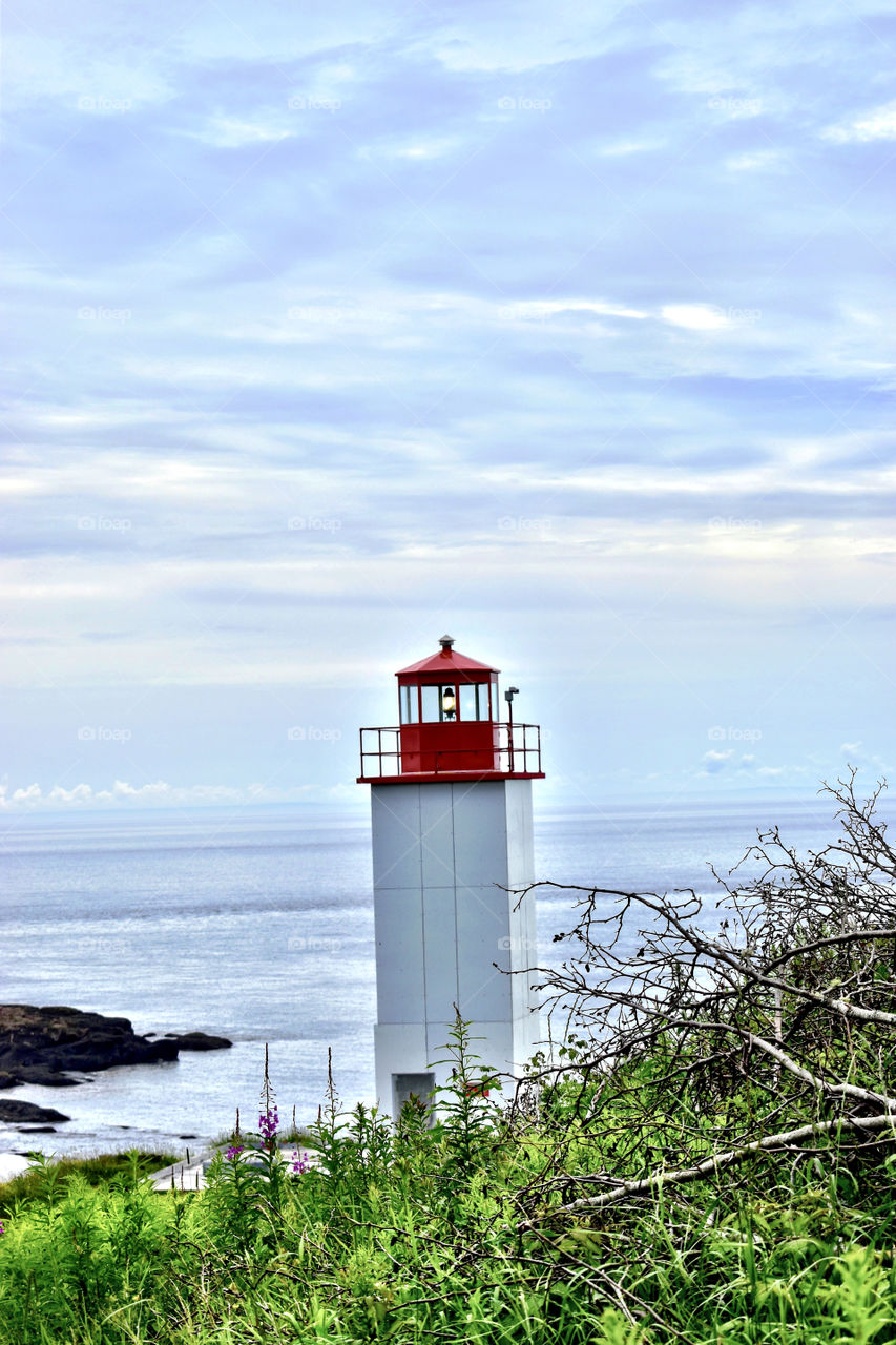 A lighthouse down by the ocean in New Brunswick Canada on a summer road trip to see the beauty of Canada 