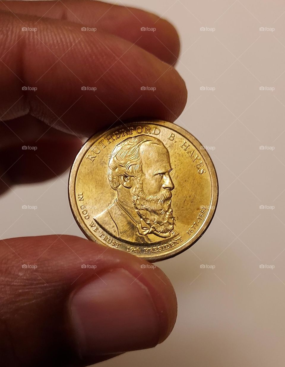 Round circle $1 coin held between the fingertips of a hand