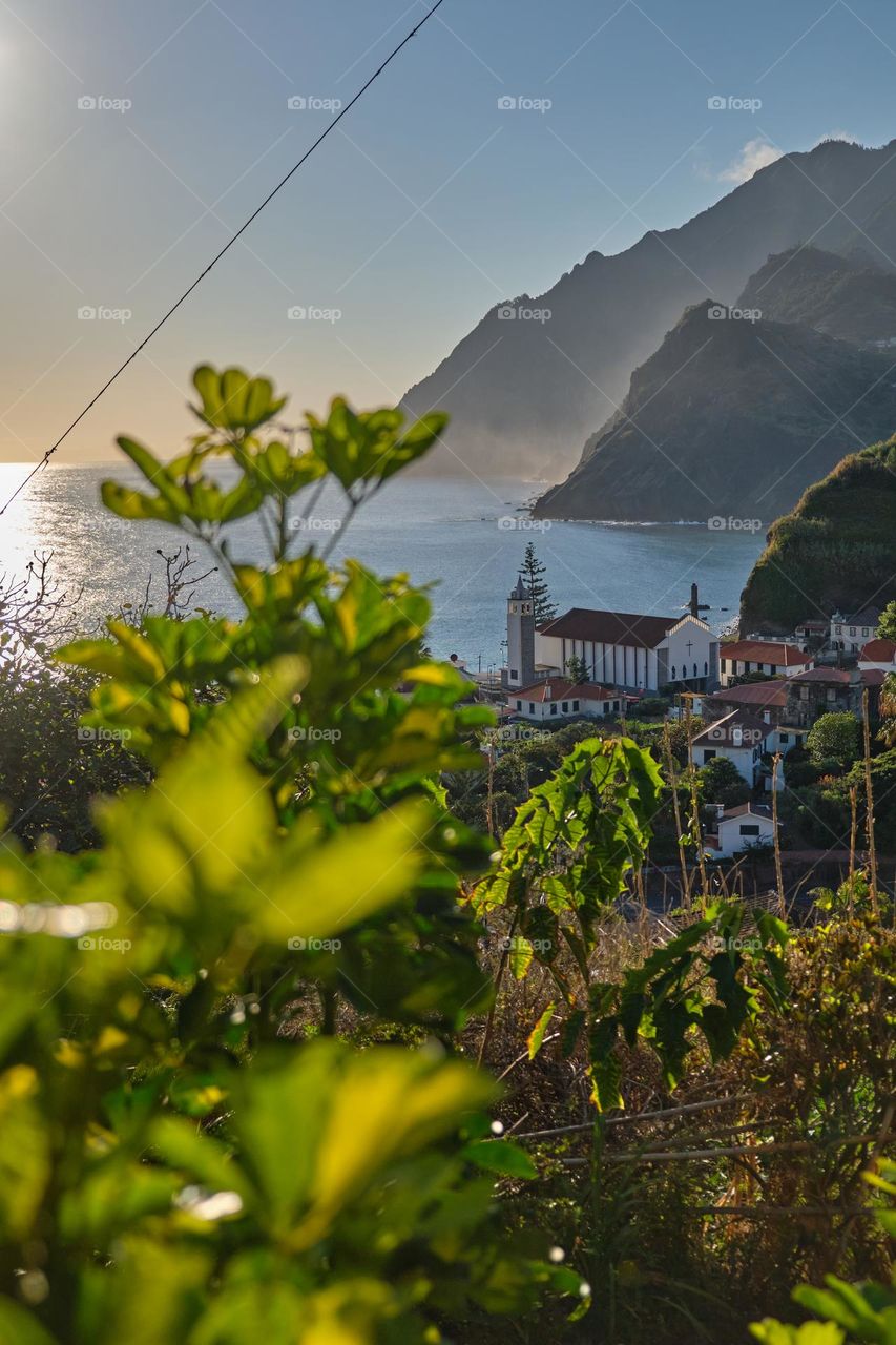 View of the church of Porto da Cruz through the green vegetation and the north coast of the island of Madeira
